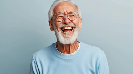 Wall Mural - A man with a big smile on his face is wearing glasses and a blue shirt. He is laughing and he is happy. laughing old man, beard, glasses, happy, open laugh, enthusiastic, light blue sweater