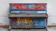 Vintage upright piano with peeling blue and red paint, showcasing a distressed and weathered look, set against a neutral background.