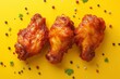 Delicious crispy chicken wings with herbs and spices on yellow background