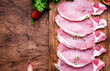 Raw pork chops on wooden board prepared for cooking with spices and pepper. Wood kitchen table background,  top view