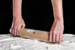 Baker hands with rolling pin on flour on black background. Baking concept.