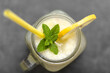 Fresh summer drink with straw. Jar glass of lemonade with lemons and mint on dark background.