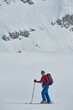 © .shock - A female skier stands at the snowy summit of a mountain, equipped with professional gear and skis, poised for an exhilarating descent.
