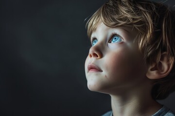 Wall Mural - Portrait of a little boy with blue eyes on a dark background