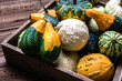 Fresh pumpkins in the box on wooden background. Farmer market with decorative vegetables. Autumn harvest and Thanksgiving concept.