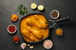 Tasty chicken curry and ingredients on black textured table, flat lay