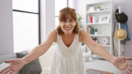 Wall Mural - Excited middle-aged woman, surprised with a smart idea, pointing finger up in a trustful success expression. sitting on house sofa, wearing dress, happy face beaming