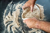 Fototapeta Uliczki - Männerhände kneten massieren und rollen einen Teig auf einer Arbeitsoberfläche in der Küche zu Hause aus