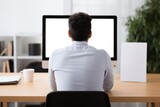 Fototapeta Kwiaty - Back view of a man working at a dual-monitor computer setup in an office environment. Professional at Computer Workstation from Behind