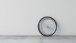A single bicycle wheel leaning against a white wall on a gray floor.