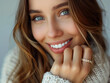 A gorgeous slightly smiling young woman wearing a ring on a hand touching chin 