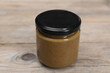 Tasty nut paste in jar on wooden table, closeup