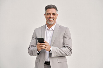 Portrait of happy middle aged business man wearing suit using mobile cell phone looking at camera isolated on white. Smiling older businessman holding cellphone using banking finance app on smartphone