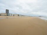 Fototapeta  - Oostende, Belgium - July 31st: Wide beach in front of the city skyline with modern buildings