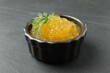 Fresh pike caviar in bowl on black table