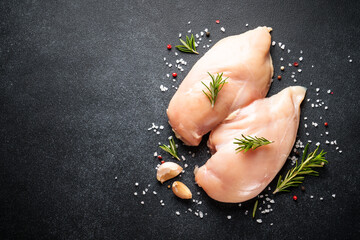 Wall Mural - Uncooked chicken breast with spices at black table. Top view with space for text.