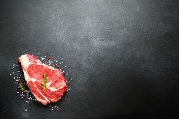 Wall Mural - Beef steak. Ribeye steak raw meat on black. Top view with copy space.