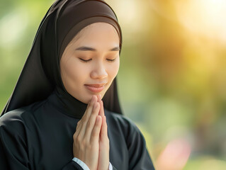 A woman wearing a black head scarf is praying. She is looking at the camera with a peaceful expression