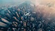 Drone aerial view captures a cityscape dominated by towering skyscrapers and high-rise buildings. The urban landscape is densely packed with structures, showcasing the bustling activity and modern