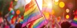 Closeup of crowd waving rainbow flags at gay pride parade, with a blurred depth background and bokeh effect