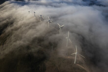 A Curvy Line Of Wind Turbines And A Thin Cloud
