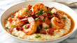Classic american dish of shrimp over creamy grits garnished with crispy bacon and green onions