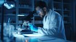 © Nicholas - A diligent lab technician in protective gear meticulously studies a sample using a microscope in a dimly lit lab