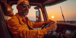 Driver with grey beard and glasses turns steering wheel of truck at sunset time. Skilled chauffeur drives lorry to deliver freight. Cargo shipping service.