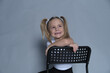 Smiling young girl resting on the back of a chair, her playful pigtails and cheerful demeanor brightening the room.