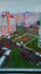 Wall Mural - Rain drop on window at rainy day. Raindrops on window flowing down on glass on the city background. Rainy weather in town. Vertical video