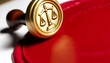 Close-up of an embossed gold seal with the scales of justice engraved on it. The seal is imprinted in red wax on an official document, symbolizing the authority and integrity of legal proceedings.