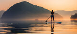 Fototapeta Boho - Silhouette of a young woman paddleboarding on the serene sea at sunset, blending fitness with relaxation.
