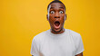 young shocked african american guy in white oversized t-shirt is surprised on yellow isolated background 