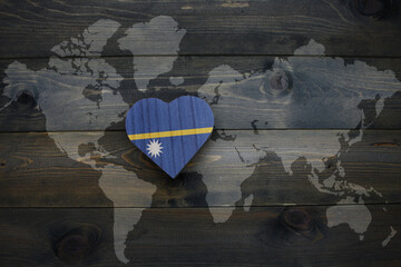Wall Mural - wooden heart with national flag of Nauru near world map on the wooden background.