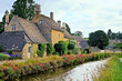 Cotswolds village of Lower Slaughter with flower lined river at dusk, Gloucestershire, England