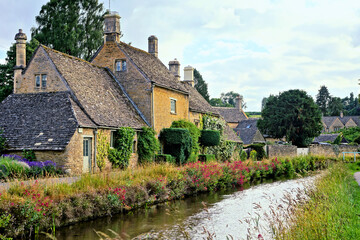 Wall Mural - Cotswolds village of Lower Slaughter with flower lined river at dusk, Gloucestershire, England