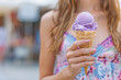 young woman enjoying a scoop of lavender ice cream in a waffle cone on a sunny day