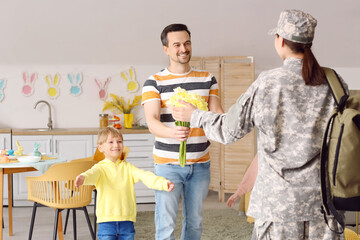 Wall Mural - Young man with tulips and his little children meeting military mother at home on Easter Day