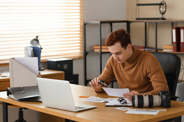 Wall Mural - Male spy with magnifier and fingerprints working at table in office in office