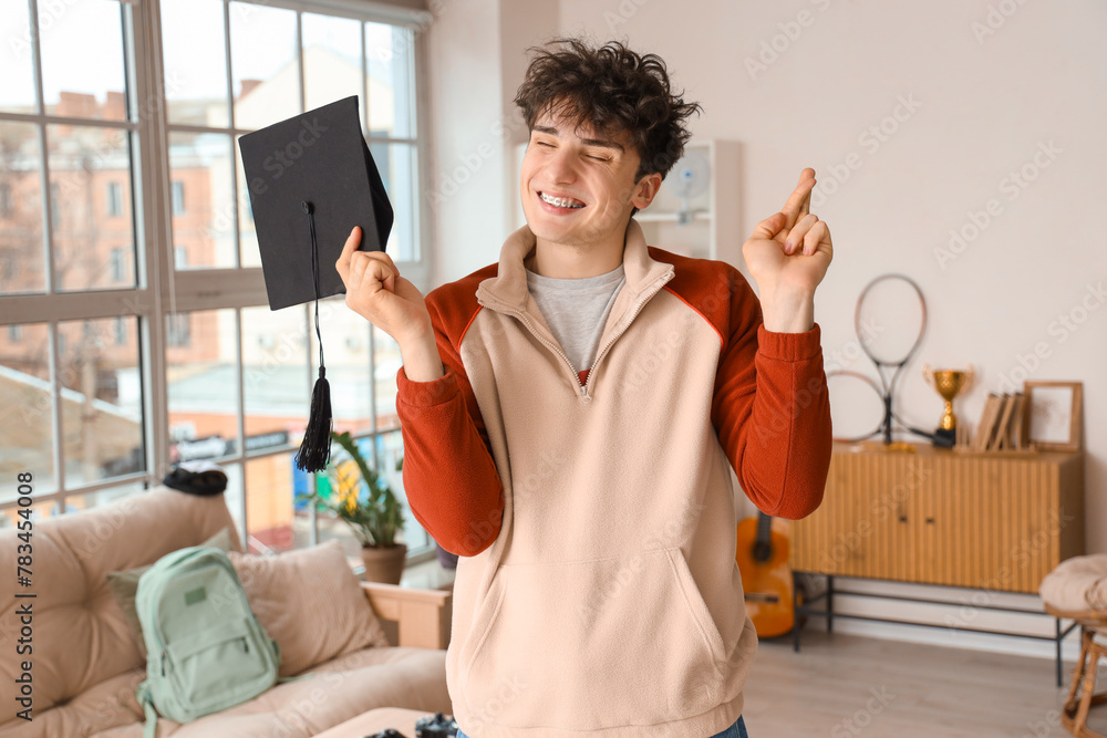Male graduate student with mortar board at home