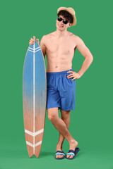 Wall Mural - Handsome young happy man with surfboard on green background