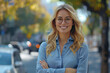 © AW AI ART - A woman with long blonde hair and glasses is smiling for the camera. She is wearing a blue shirt and is standing on a street