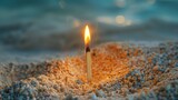 Fototapeta  - A single matchstick burning and standing upright on a bed of sand for illustrating fire safety or ignition hazards