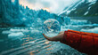 A hand holding a crystal glass earth globe with thr background of melting glaciers, depicting global warming across the world