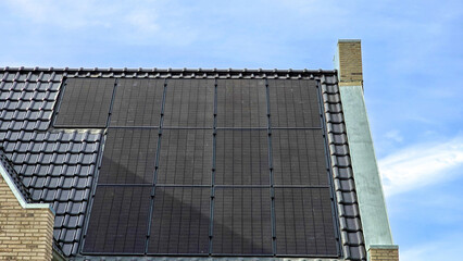 Poster - Dutch Suburban area with black solar panels on the roof against a sunny sky Close up of new house with black solar panels. Zonnepanelen, Zonne energie, Translation: Solar panel, Sun Energy