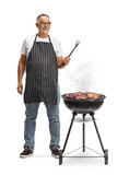 Fototapeta Panele - Mature man next to a portable barbecue grill holding a fork