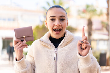 Canvas Print - Young moroccan girl holding a wallet at outdoors pointing up a great idea