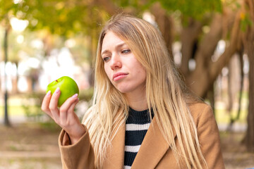 Young pretty blonde woman with an apple at outdoors