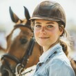 Young woman with a brown riding helmet and a blue shirt standing next to her horse.