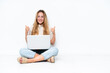 © luismolinero - Young woman with laptop sitting on the floor isolated on white background with thumbs up gesture and smiling